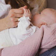 Baby liegt gestützt vom Bio-Stillkissen auf dem Schoss seiner Mutter